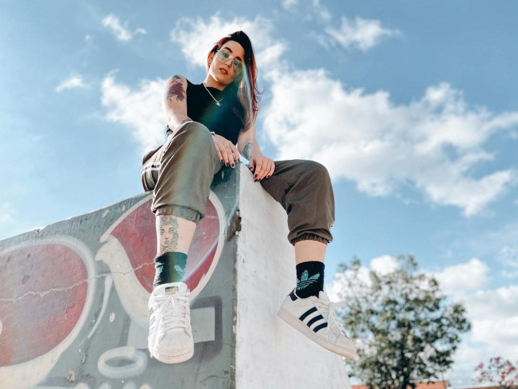 Rebellische tätowierte Dame entspannt sich im Skatepark an einem sonnigen Tag