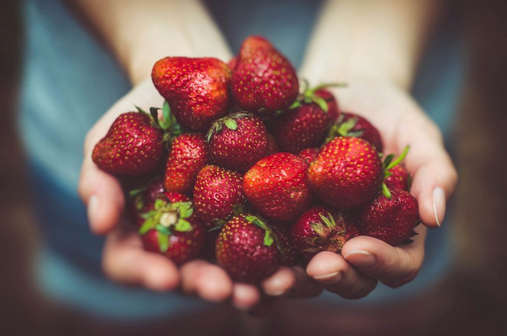 Unscharfe Fotografie von Erdbeeren auf der Handfläche einer Person