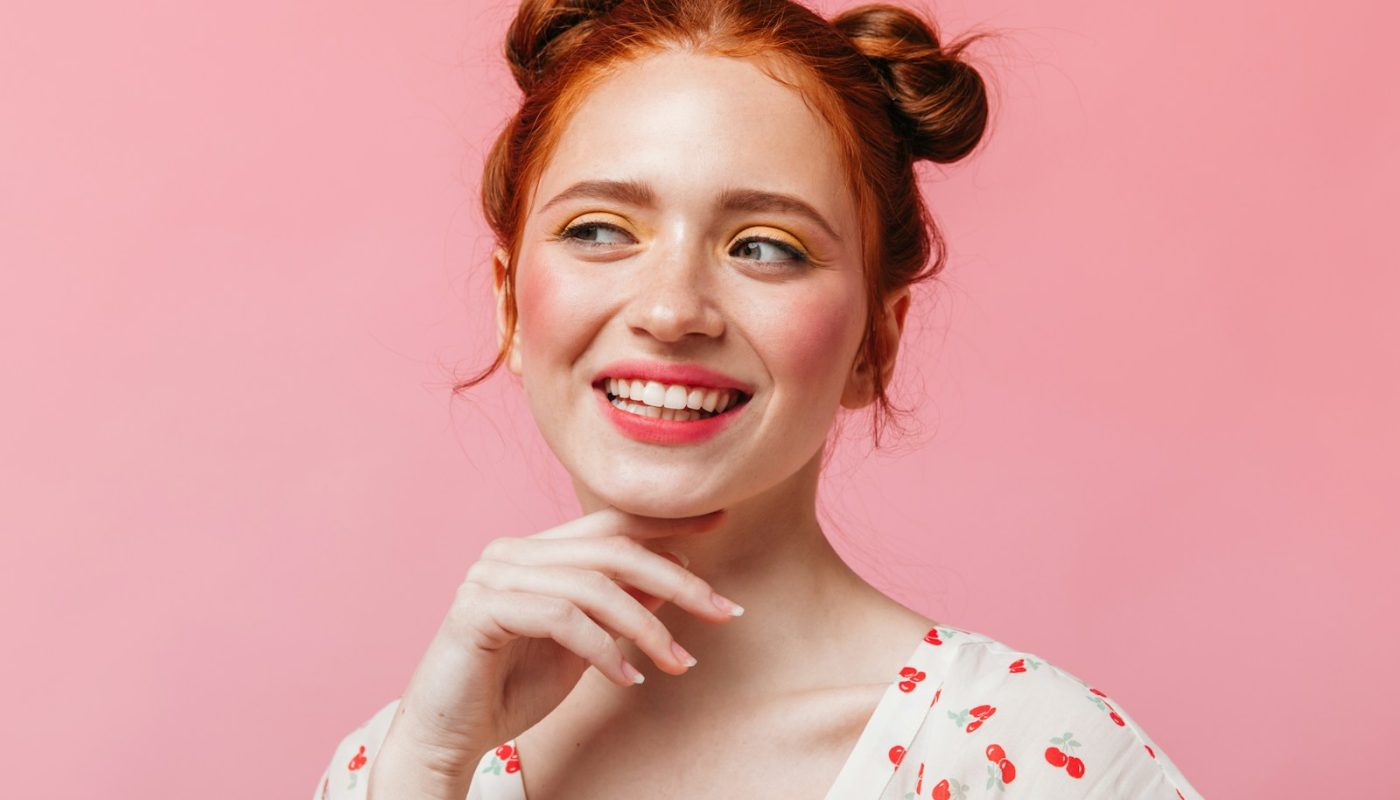 eine Frau mit roten Haaren lächelt und posiert für ein Foto