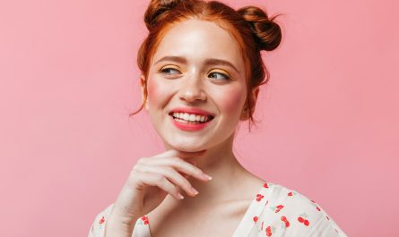 eine Frau mit roten Haaren lächelt und posiert für ein Foto