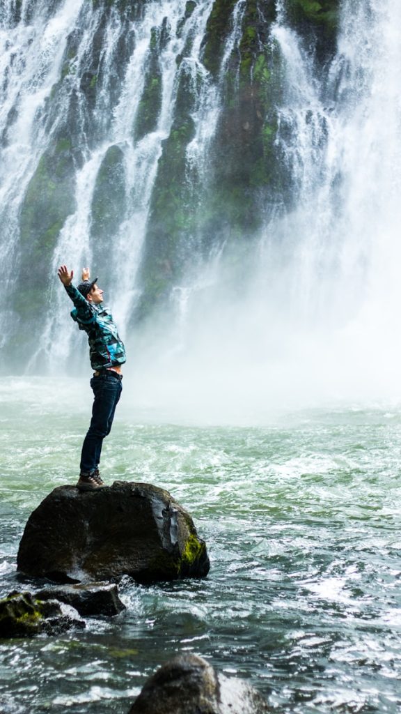 Mann steht auf schwarzem Felsen, umgeben von Wasser