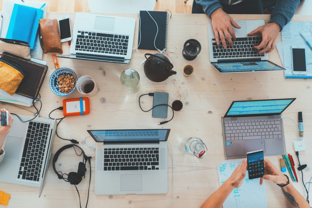 Menschen, die sich an einen Tisch mit verschiedenen Laptops setzen